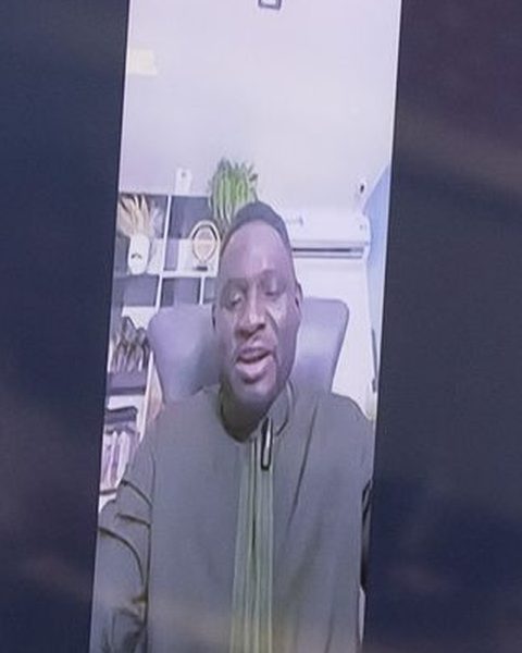 Rotimi Ojamamoye on the screen in the room, live on Zoom